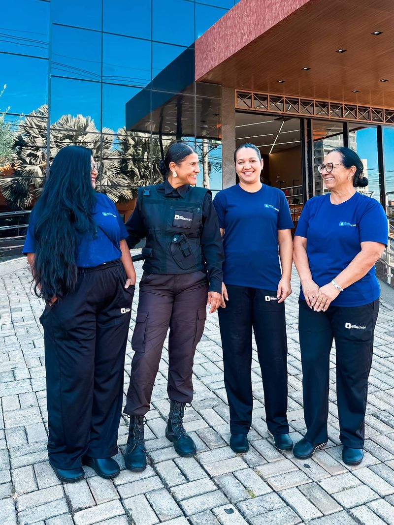 Quatro colaboradoras, uma delas de portaria, em frente a um prédio comercial